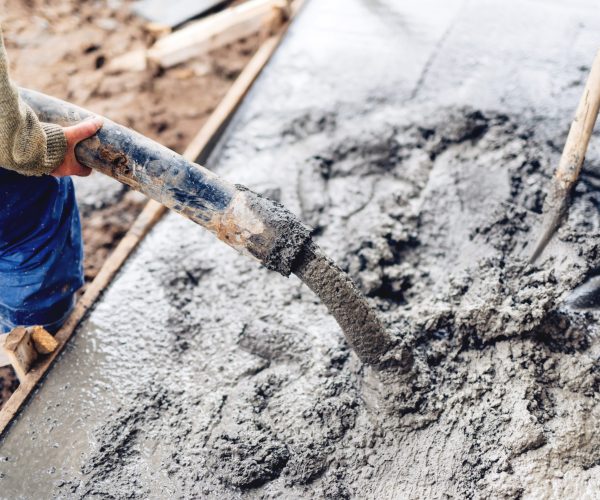 industrial construction workers using automatic pump tube for pouring cement on reinforcement bars